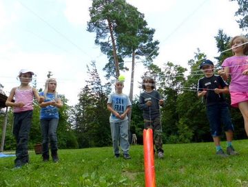 Die Kinder balancieren im Team einen Tennisball in einem Fadenkreuz